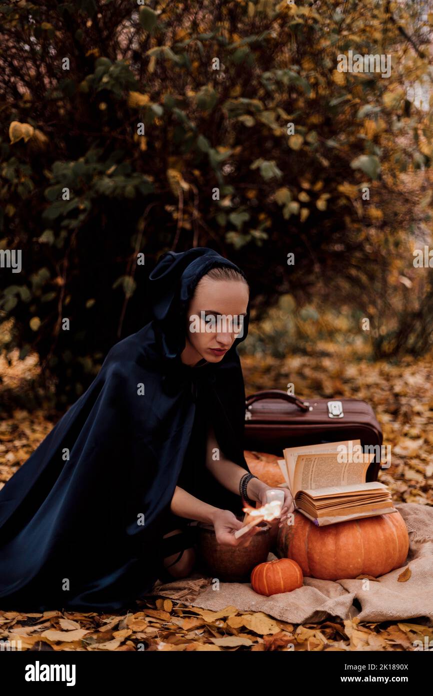 Una giovane donna nei boschi pratica la magia di Halloween Foto Stock