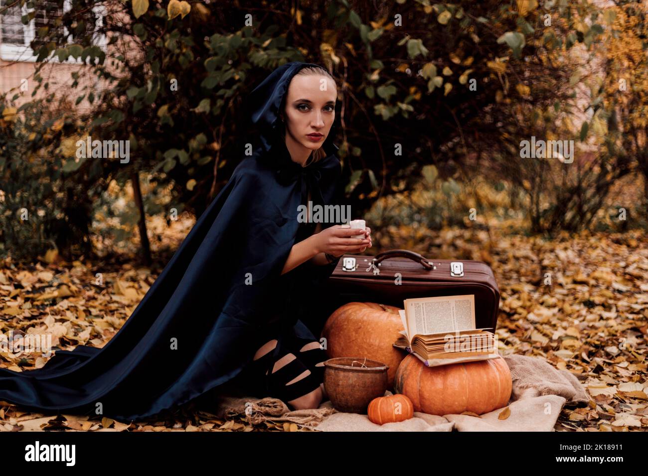 Una giovane donna nei boschi pratica la magia di Halloween Foto Stock
