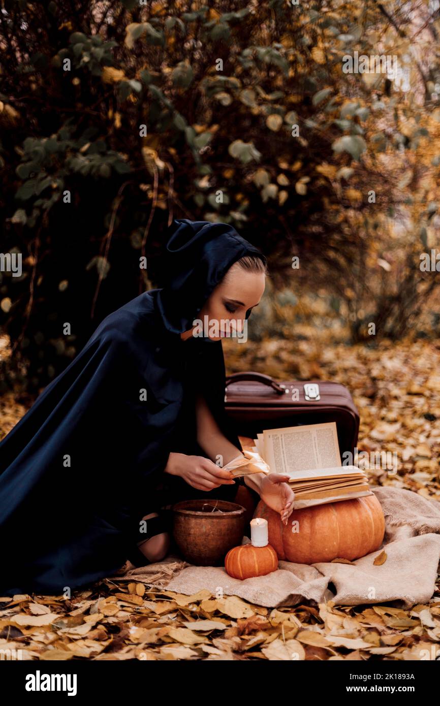 Una giovane donna nei boschi pratica la magia di Halloween Foto Stock