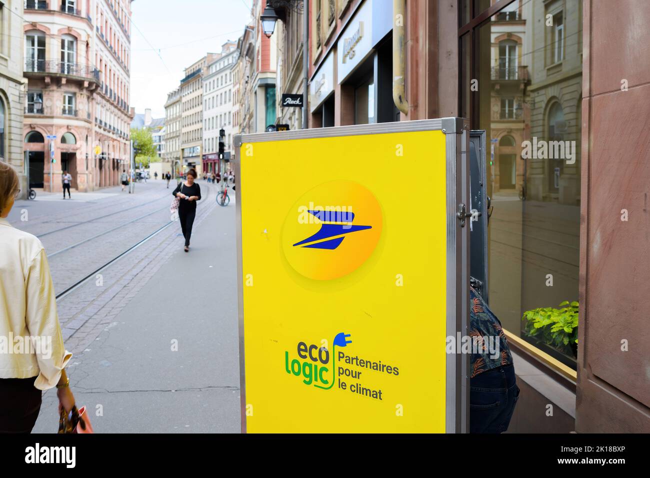 Strasburgo, Francia - 9 settembre 2022: Vista posteriore del lavoratore postale alla ricerca di pacchi lettera nel suo carrello della bici elettrica consegna pacchi Foto Stock