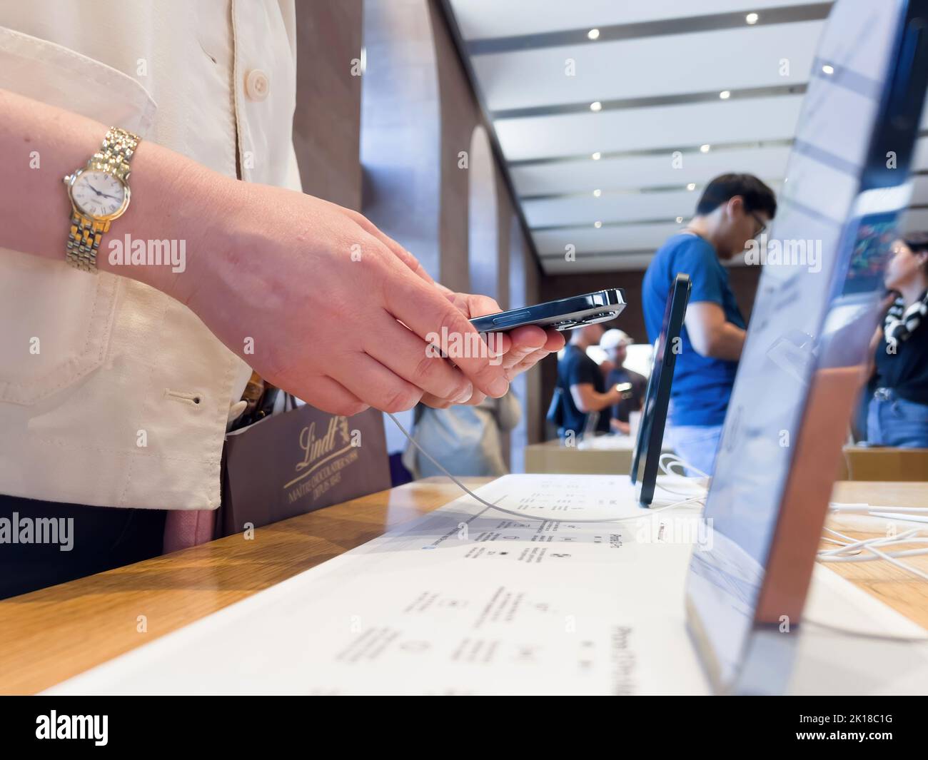 Parigi, Francia - 9 settembre 2022: Vista laterale della donna che tiene in mano ultimi computer Apple iPhone 14 pro smartphone all'interno di Apple Store guardando le nuove funzionalites del telefono professionale smartphone Foto Stock