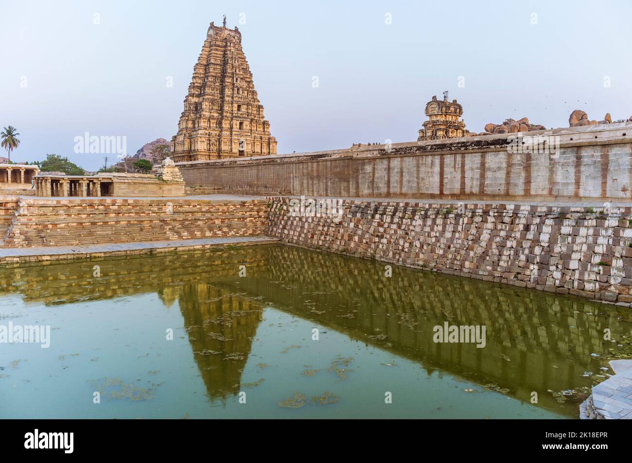 Hampi, Karnataka, India: 7th ° secolo gopuram torre del Tempio di Sree Virupaksha riflesso sul serbatoio dell'acqua. Si ritiene che funzioni ininterrottamente Foto Stock