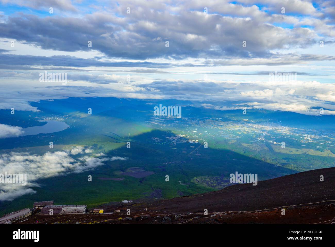 Rifugi sulle pendici del Monte Fuji con grande ombra che domina il paesaggio sullo sfondo Foto Stock
