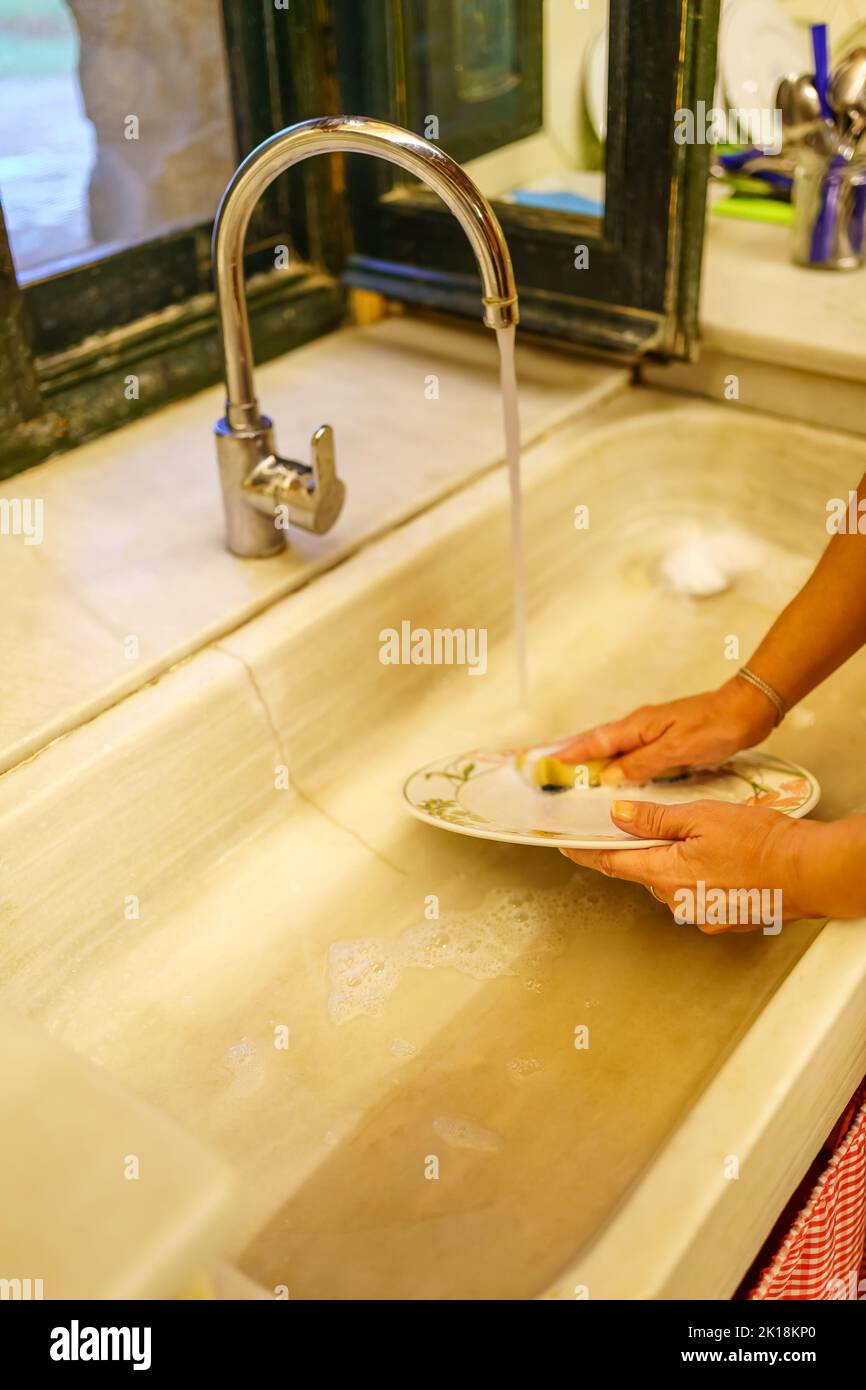 Piatti di lavaggio donna in un lavello da cucina retro antico stile. Foto Stock