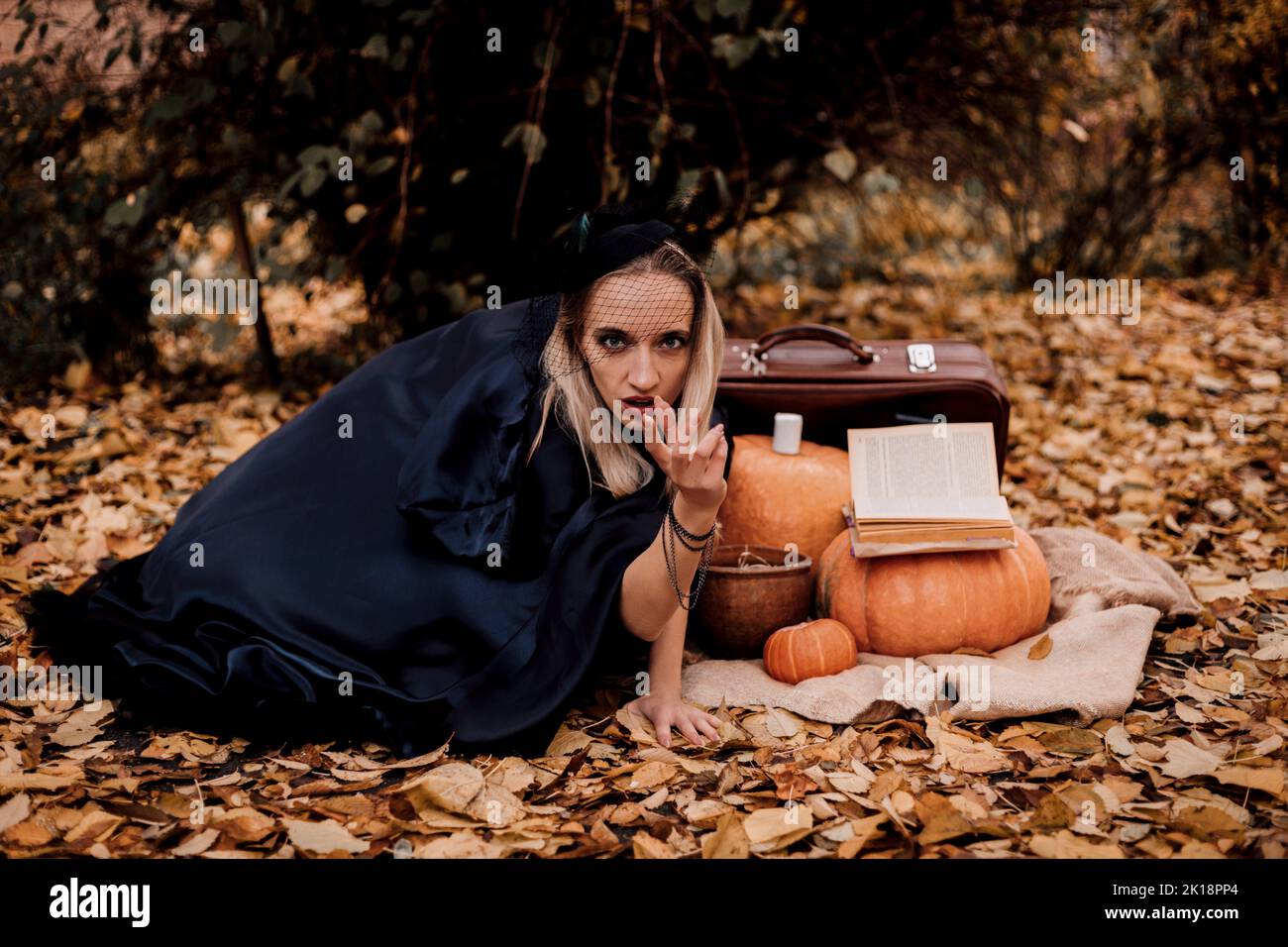 Una giovane donna nei boschi pratica la magia di Halloween Foto Stock