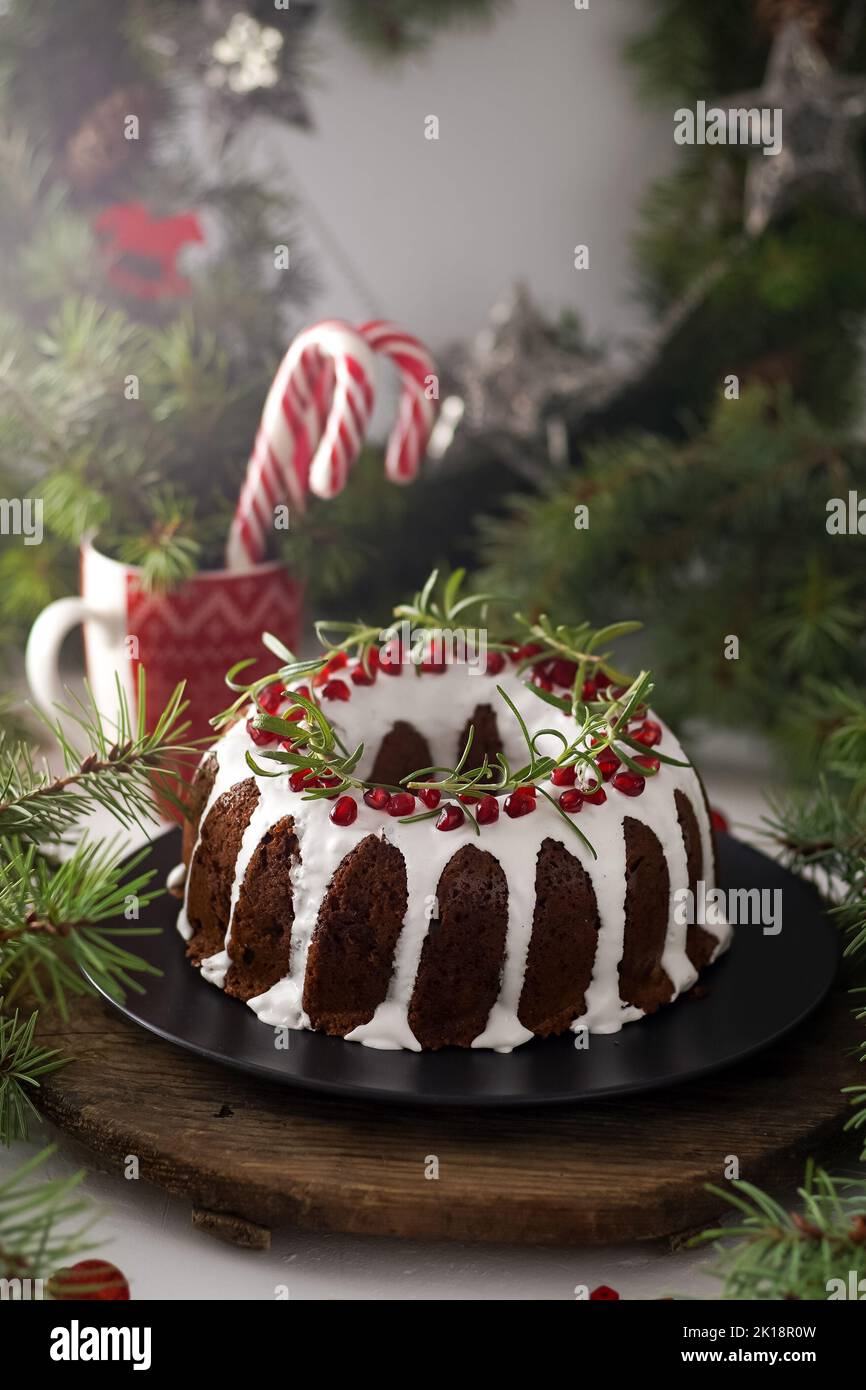 Cibo di Natale. Torta rotonda con glassa bianca. Cupcake con buco al centro con melograno. Rami di abete rosso verde sul tavolo. Vita morta. Dolci, dolci e dolci per il nuovo anno. Foto Stock