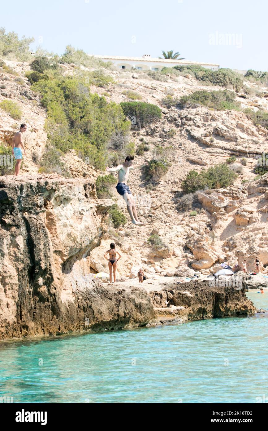 I turisti sull'isola di Ibiza possono saltare dalla scogliera saltando fuori da una roccia nel mare. L'isola ha molte insenature profonde e affioramenti rocciosi. Foto Stock