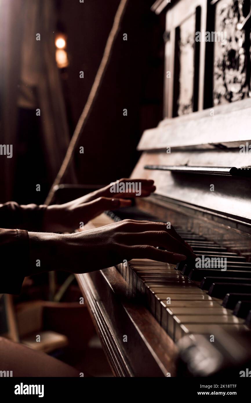 Mani umane sui tasti del pianoforte. Camera molto buia, poco luminosa Foto Stock
