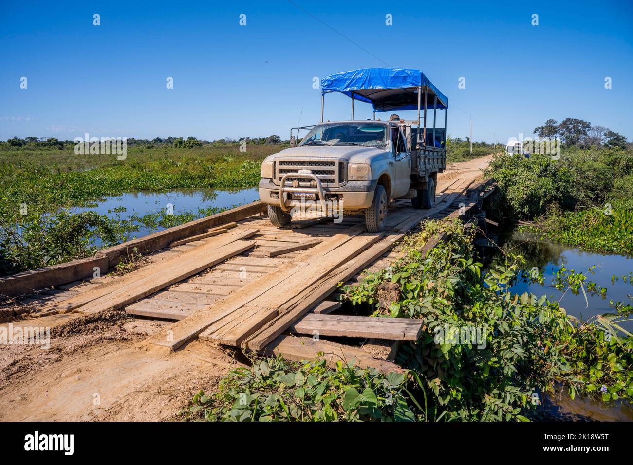 Un veicolo da safari sta attraversando uno dei vecchi ponti di legno dell'autostrada Transpantaneira nel nord di Pantanal, nella provincia del Mato Grosso del Brasile. Foto Stock