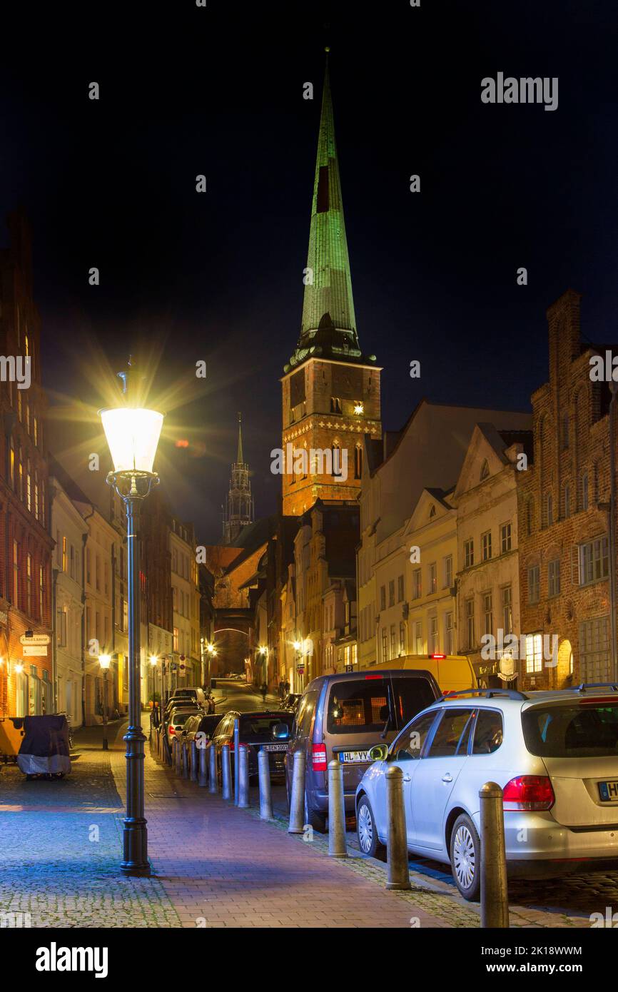La chiesa gotica Jakobikirche / San Jakobi e strada con case storiche nella città anseatica Lübeck di notte, Schleswig-Holstein, Germania Foto Stock