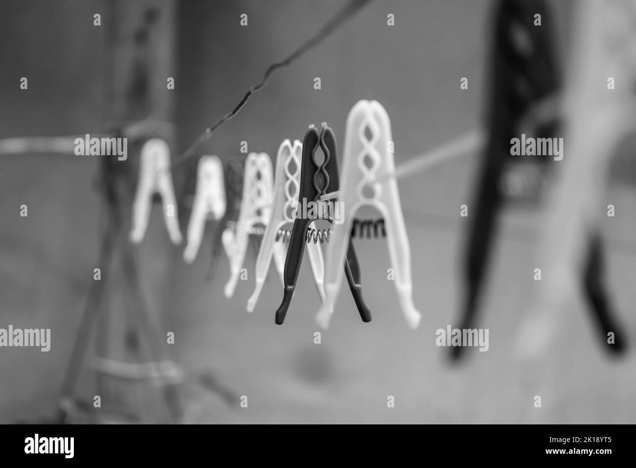 Appendiabiti allineati su clothesline, bianco e nero concetto, fuoco selettivo. Foto Stock