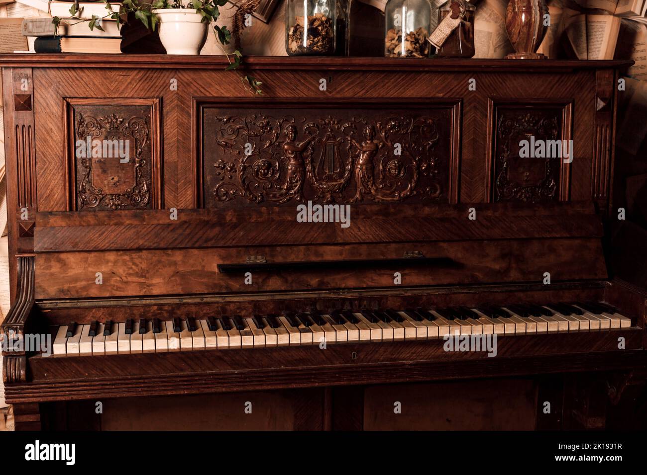 Un vecchio pianoforte in una stanza buia. Un sacco di libri sulle pareti Foto Stock