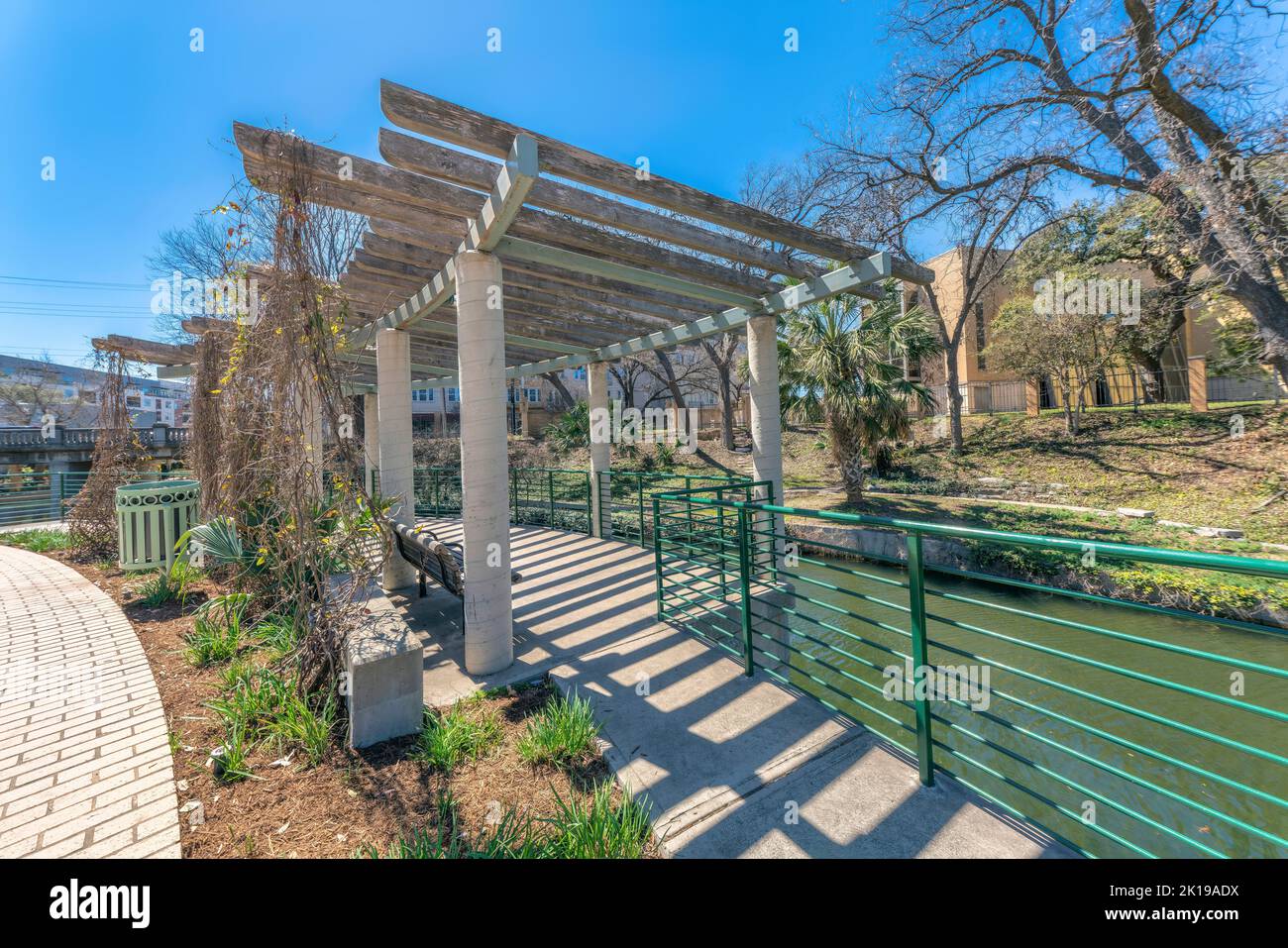 Centro di San Antonio, Texas - passeggiata sul fiume con il pergolato su un sentiero in cemento accanto al fiume. Vi è un tetto in pergola con viti secche e ringhiere tra t Foto Stock
