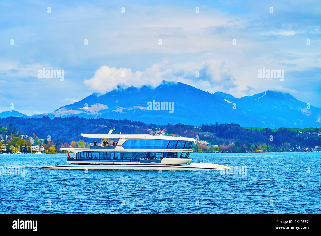 Un catamarano moderno naviga lungo la baia di Lucerna, nei dintorni delle montagne delle Alpi, in Svizzera Foto Stock