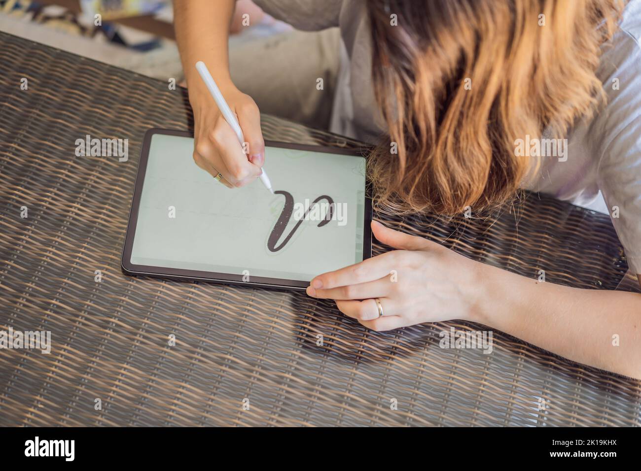 Calligrafer Young Woman scrive frase su tablet digitale. Iscrizione di lettere ornamentali decorate. Calligraphy, graphic design, lettering, graphic writing Foto Stock