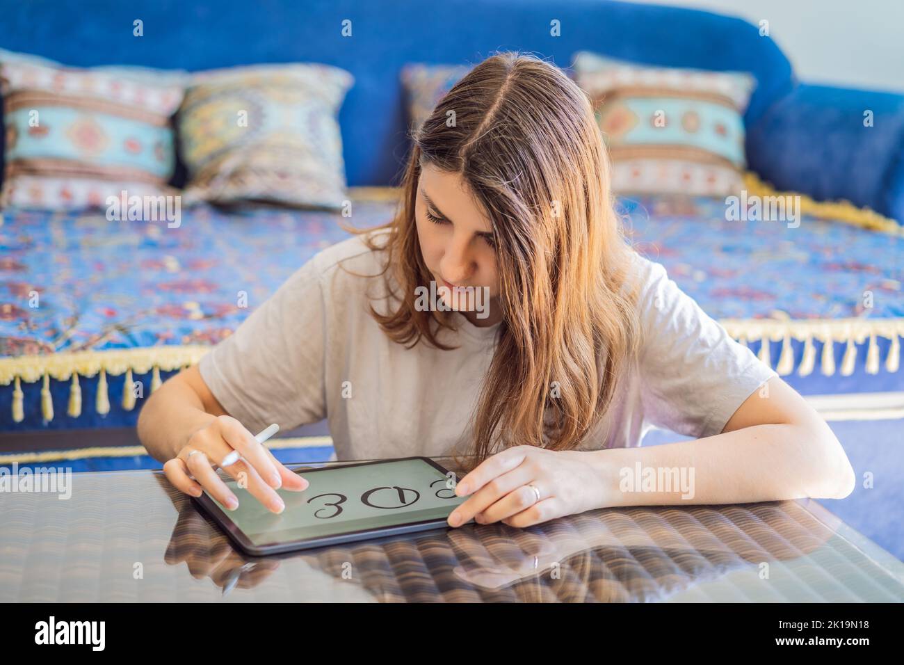 Calligrafer Young Woman scrive frase su tablet digitale. Iscrizione di lettere ornamentali decorate. Calligraphy, graphic design, lettering, graphic writing Foto Stock