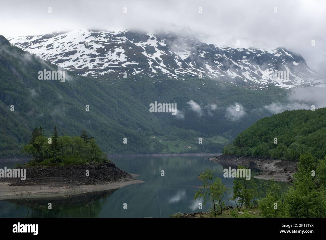 Paesaggi meravigliosi in Norvegia. Vestland. Bellissimo scenario di un'isola nel lago Roldalsvatnet. Montagne innevate e alberi su rocce sullo sfondo. Foto Stock