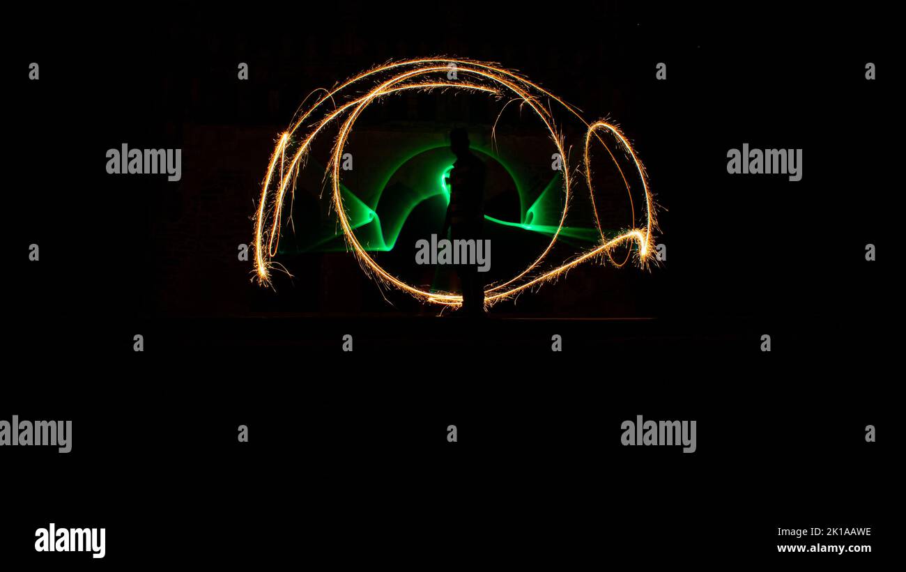 Kodanadu, Tamilnadu, India - Marzo 14 2021 : una persona in piedi contro la bella pittura a luce circolare colorata come sfondo. Luce di pittura porto Foto Stock