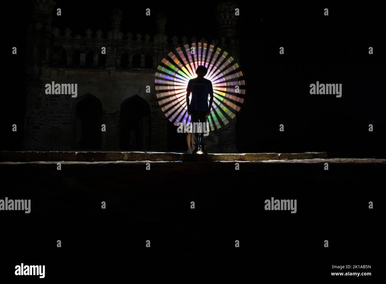 Kodanadu, Tamilnadu, India - Marzo 14 2021 : una persona in piedi contro la bella pittura a luce circolare colorata come sfondo. Luce di pittura porto Foto Stock