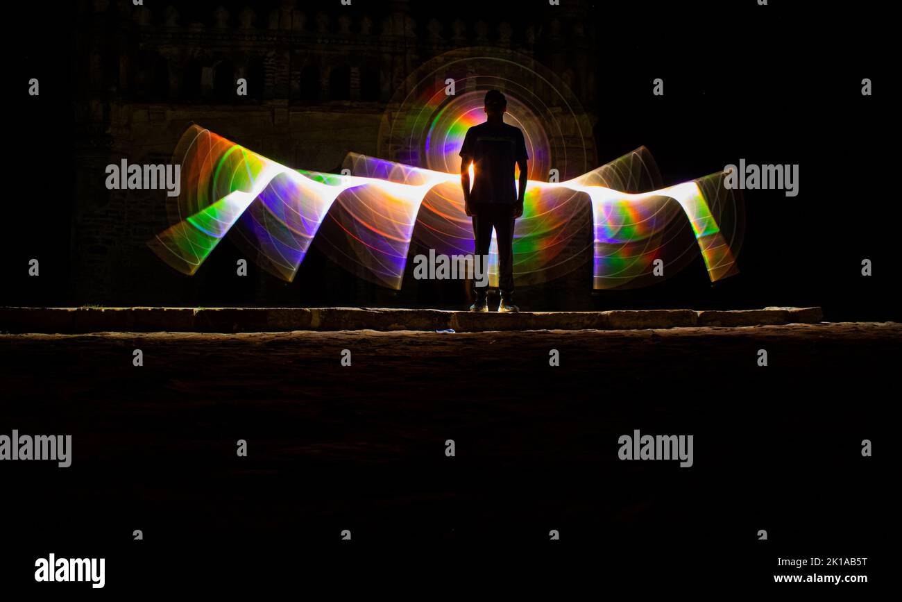 Kodanadu, Tamilnadu, India - Marzo 14 2021 : una persona in piedi contro la bella pittura a luce circolare colorata come sfondo. Luce di pittura porto Foto Stock