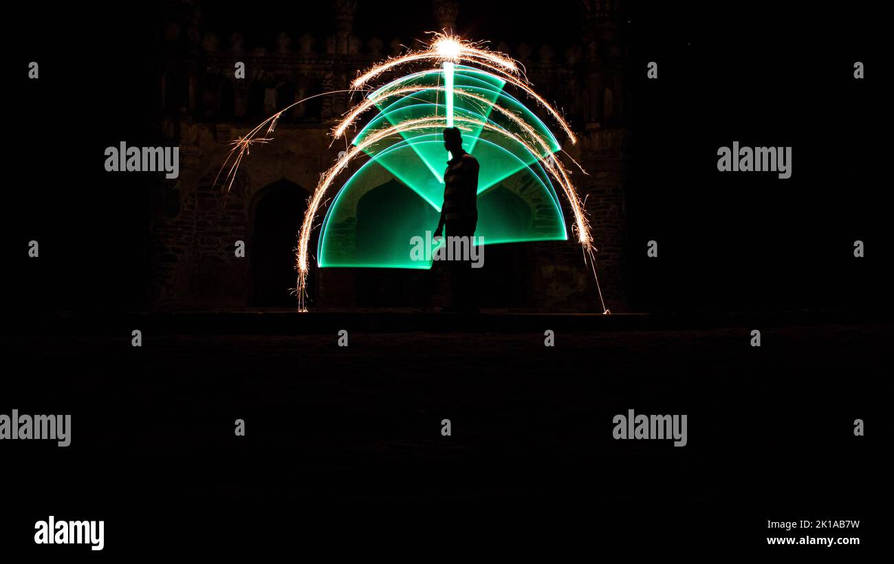 Kodanadu, Tamilnadu, India - Marzo 14 2021 : una persona in piedi contro la bella pittura a luce circolare colorata come sfondo. Luce di pittura porto Foto Stock