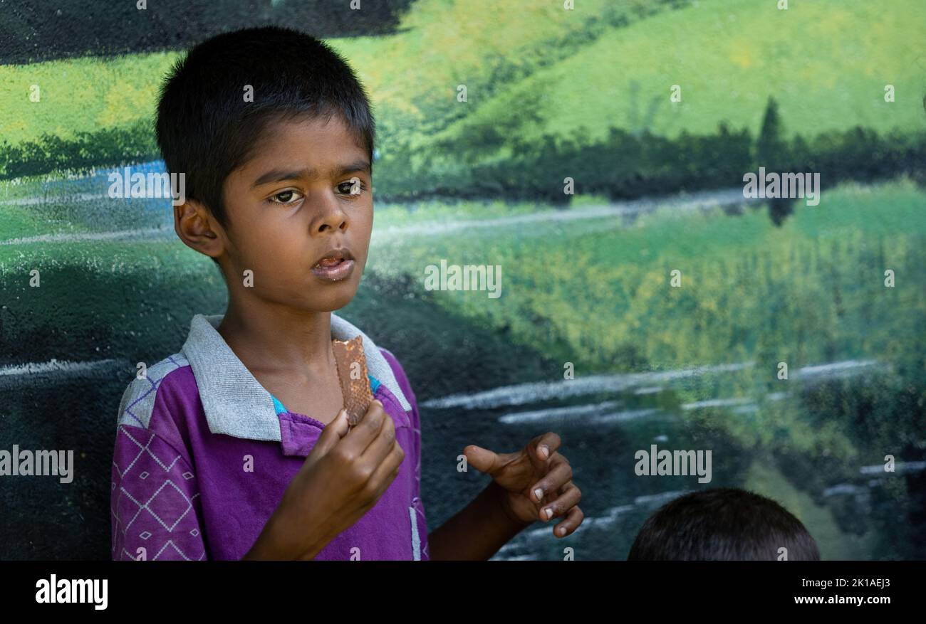 Povero ragazzo che mangia una barretta di cioccolato liberata durante la crisi in Sri Lanka, 30th luglio 2022 Foto Stock