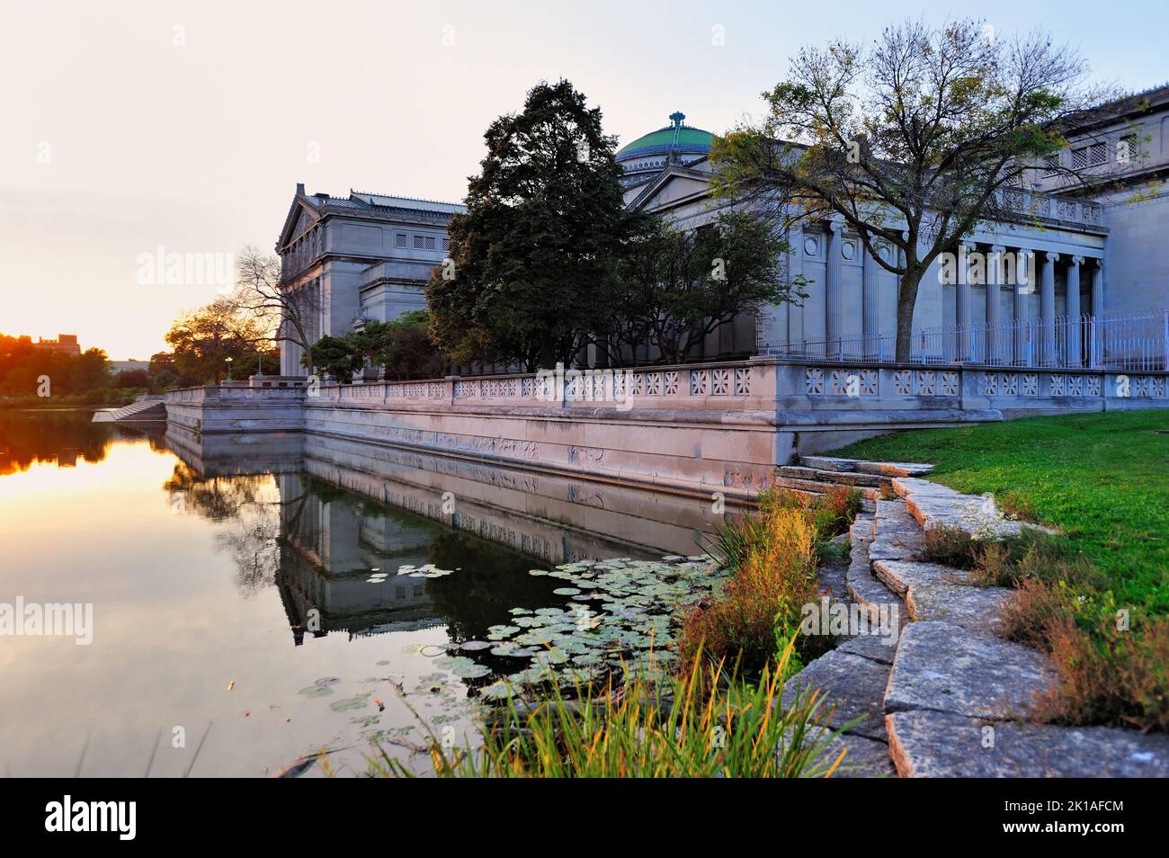 Chicago, Illinois, Stati Uniti. Museo della Scienza e dell'industria che fornisce un'immagine speculare in un laghetto riflettente appena prima del tramonto. Foto Stock