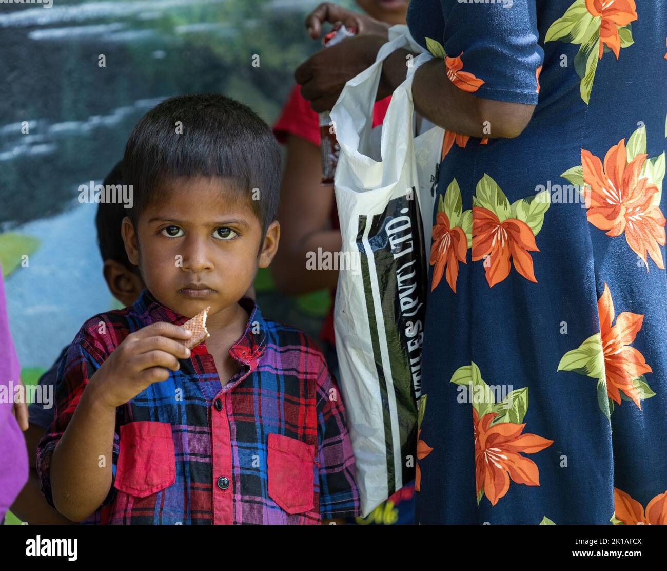 Povero bambino che mangia un cioccolato mentre tiene la mamma in Sri Lanka 30th luglio 2022 Foto Stock