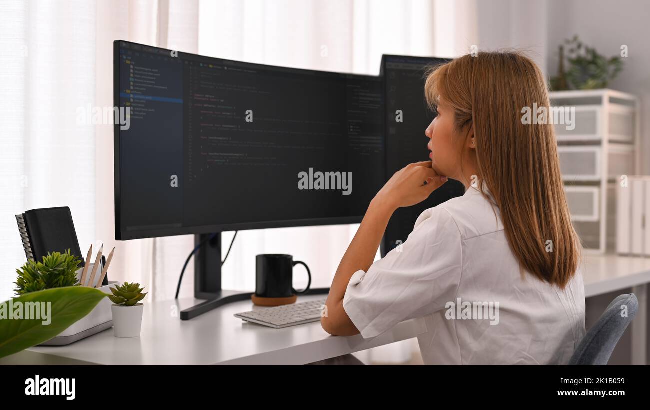 Vista laterale di un giovane sviluppatore che guarda i dati codificati sullo schermo del computer. Sviluppo del concetto di tecnologie di programmazione e codifica Foto Stock