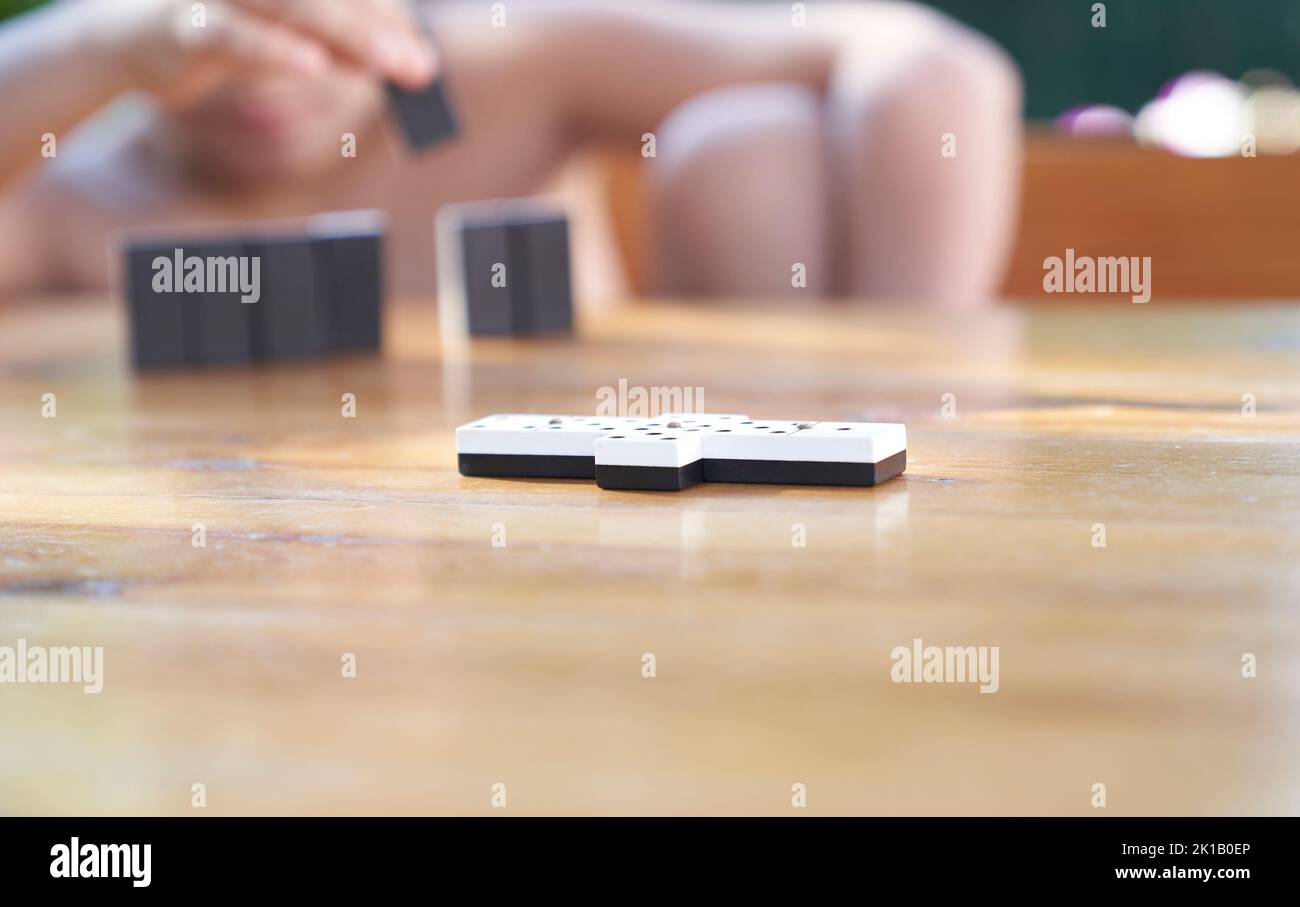 Una famiglia che gioca a domino in un tavolo di legno. Foto Stock