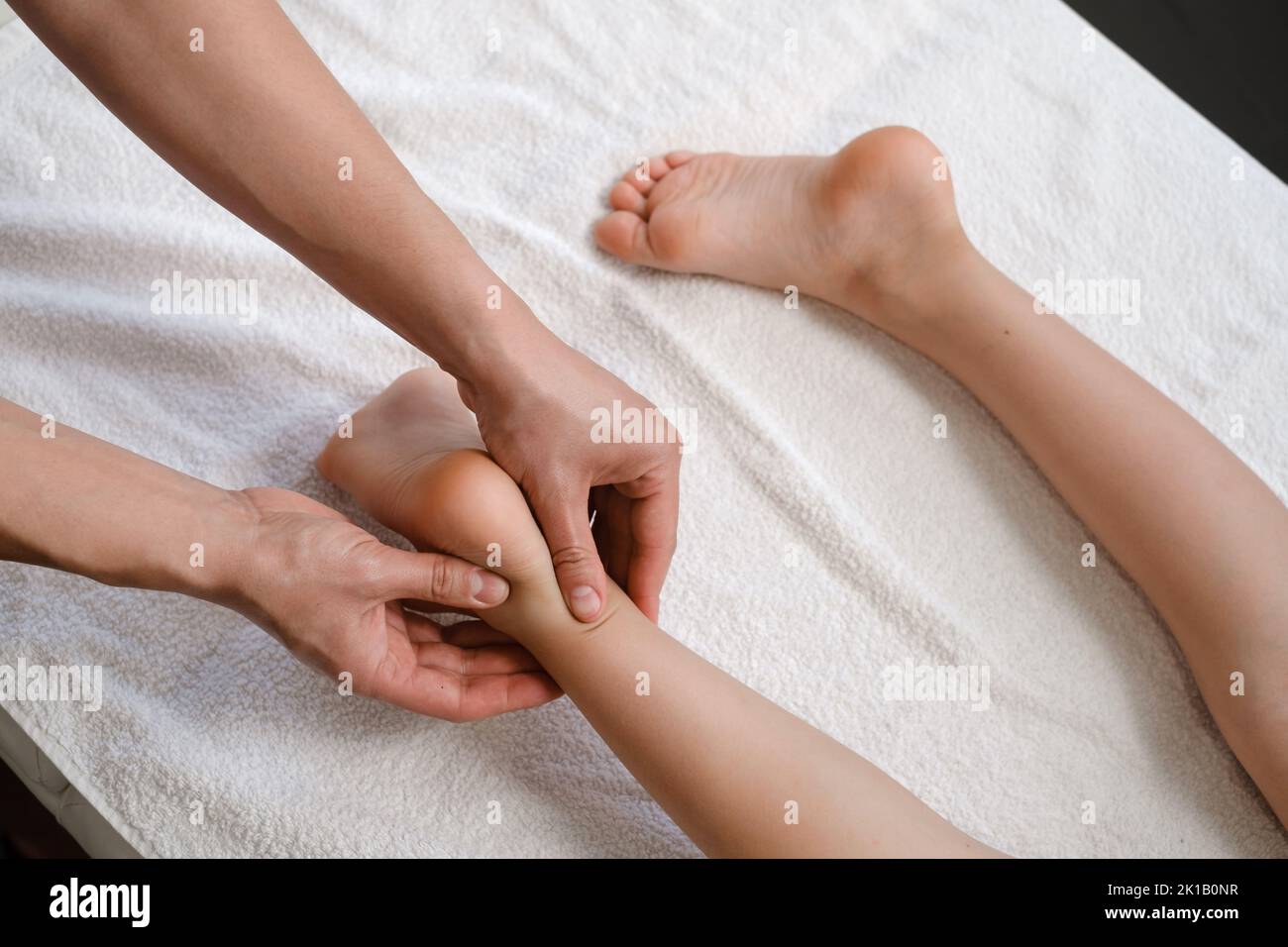 Trattamento di massaggio plantare per bambini con massaggiatore professionista nel resort termale. Benessere, sollievo dallo stress e concetto di assistenza sanitaria Foto Stock