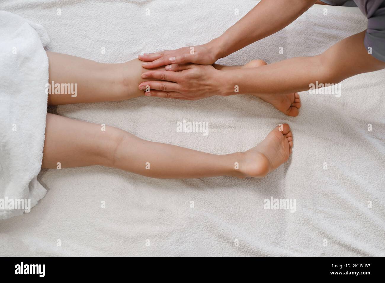 pediatra osteopatica. Esame e correzione delle gambe. Medico che tiene il piede del bambino nelle sue braccia. In clinica. Fisioterapista che dà piede Foto Stock