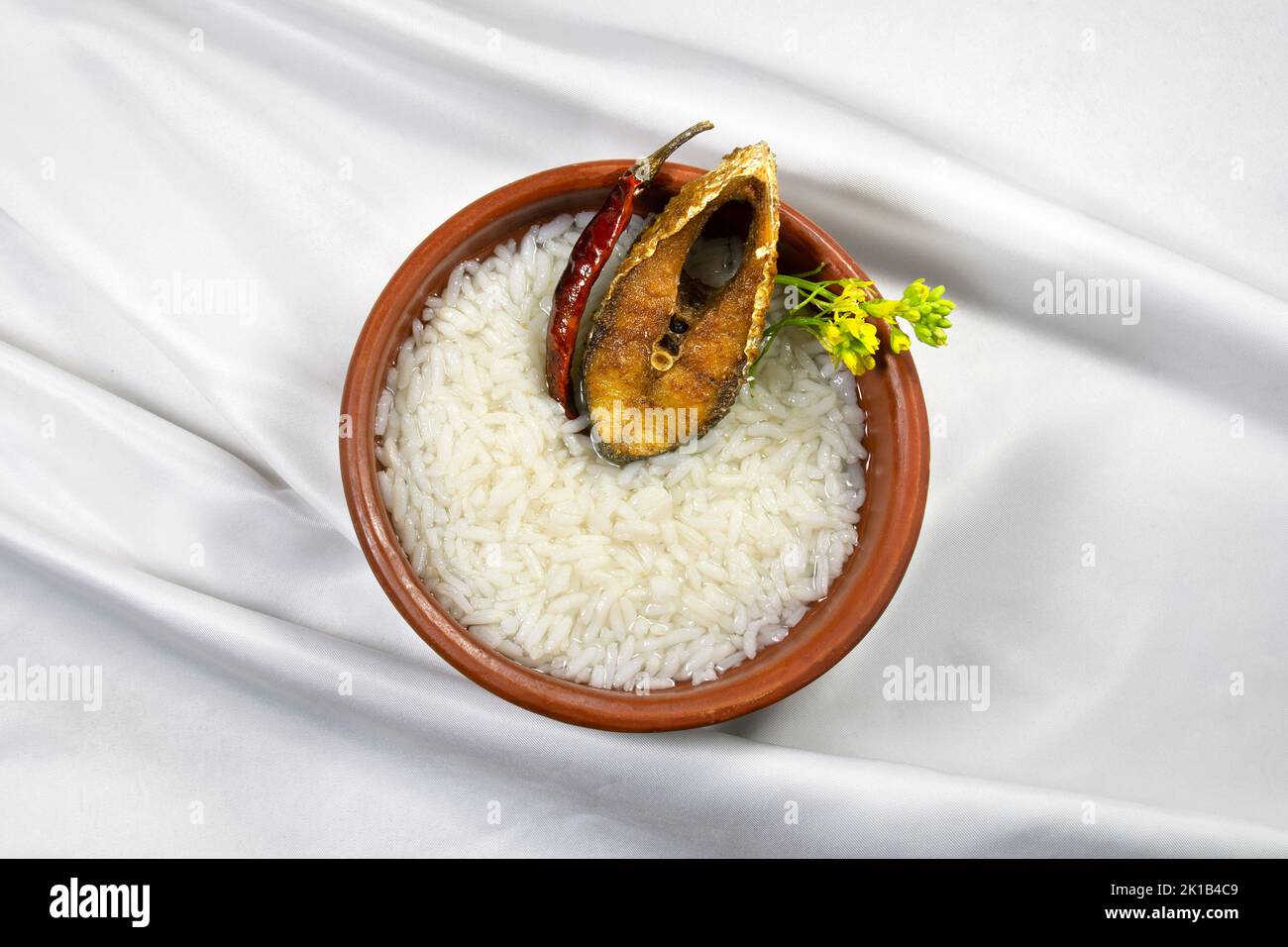 Bengalese nuovo anno piatto di festa Boishakh panta ilish con peperoncino secco e senape fiore. Panta bhat è popolare tra i bengalesi in India e Bangladesh Foto Stock