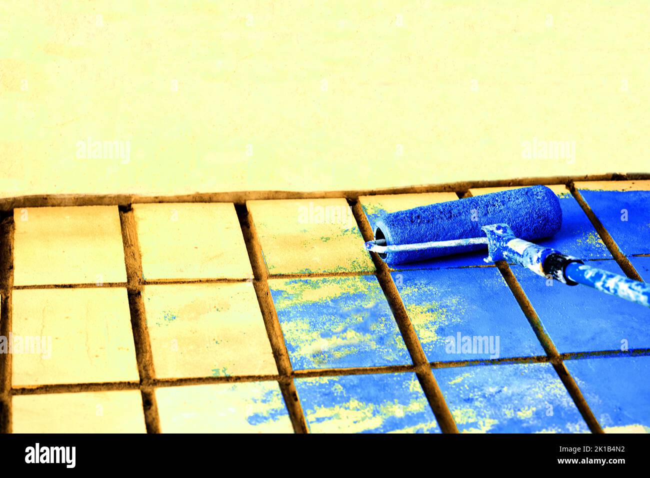 Verniciatura a rullo superficie parete gialla con vernice blu Foto Stock