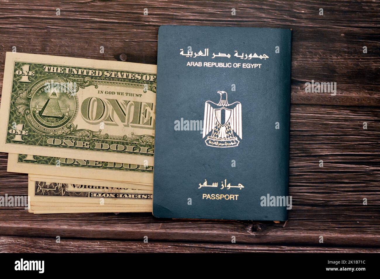 Passaporto egiziano con dollari americani di 1 $ uno banconote in denaro degli Stati Uniti isolato su sfondo di legno, Repubblica araba d'Egitto passaporto con Foto Stock