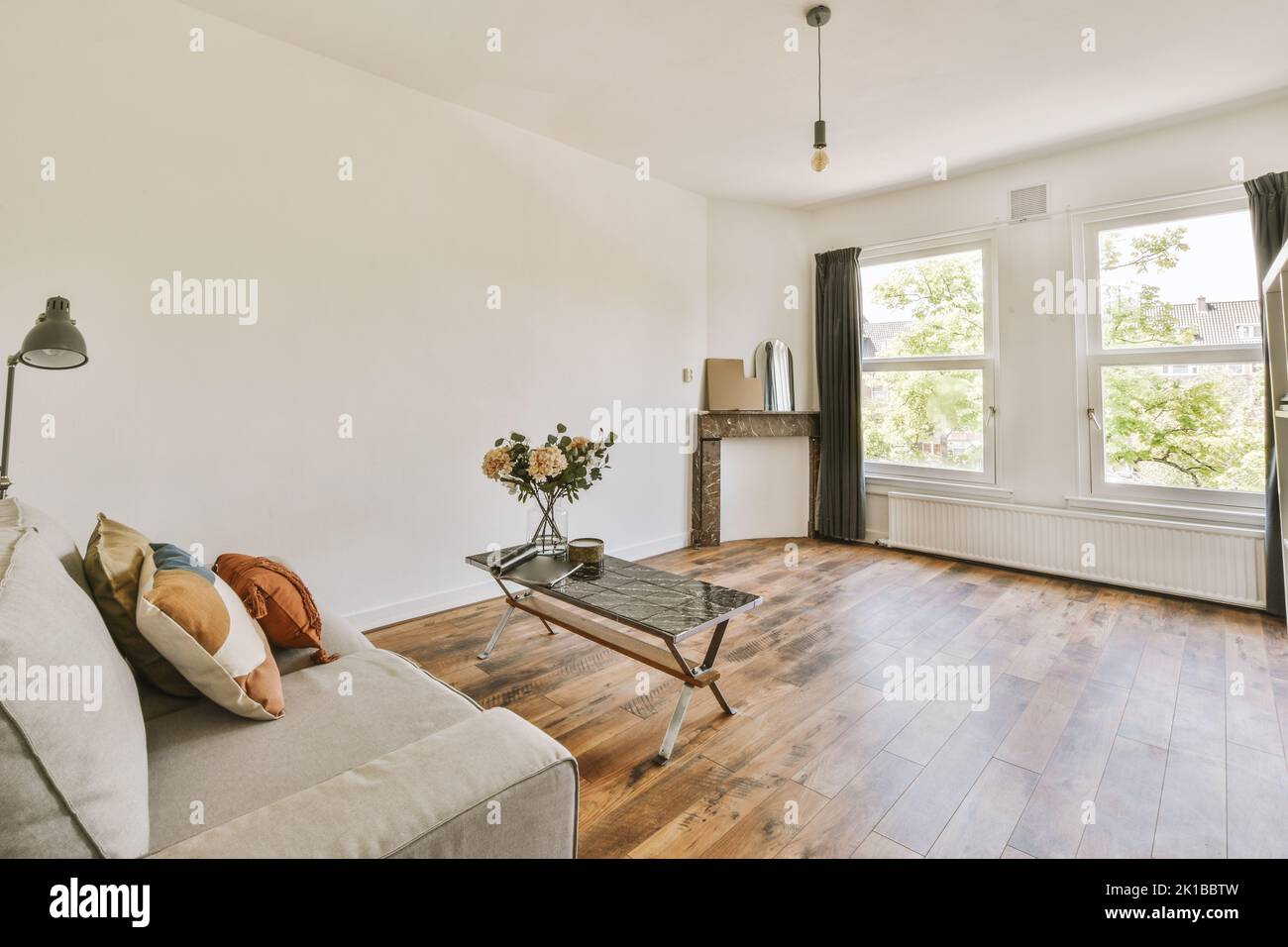 Comodo divano vicino alle finestre in un accogliente soggiorno luminoso in un moderno appartamento Foto Stock