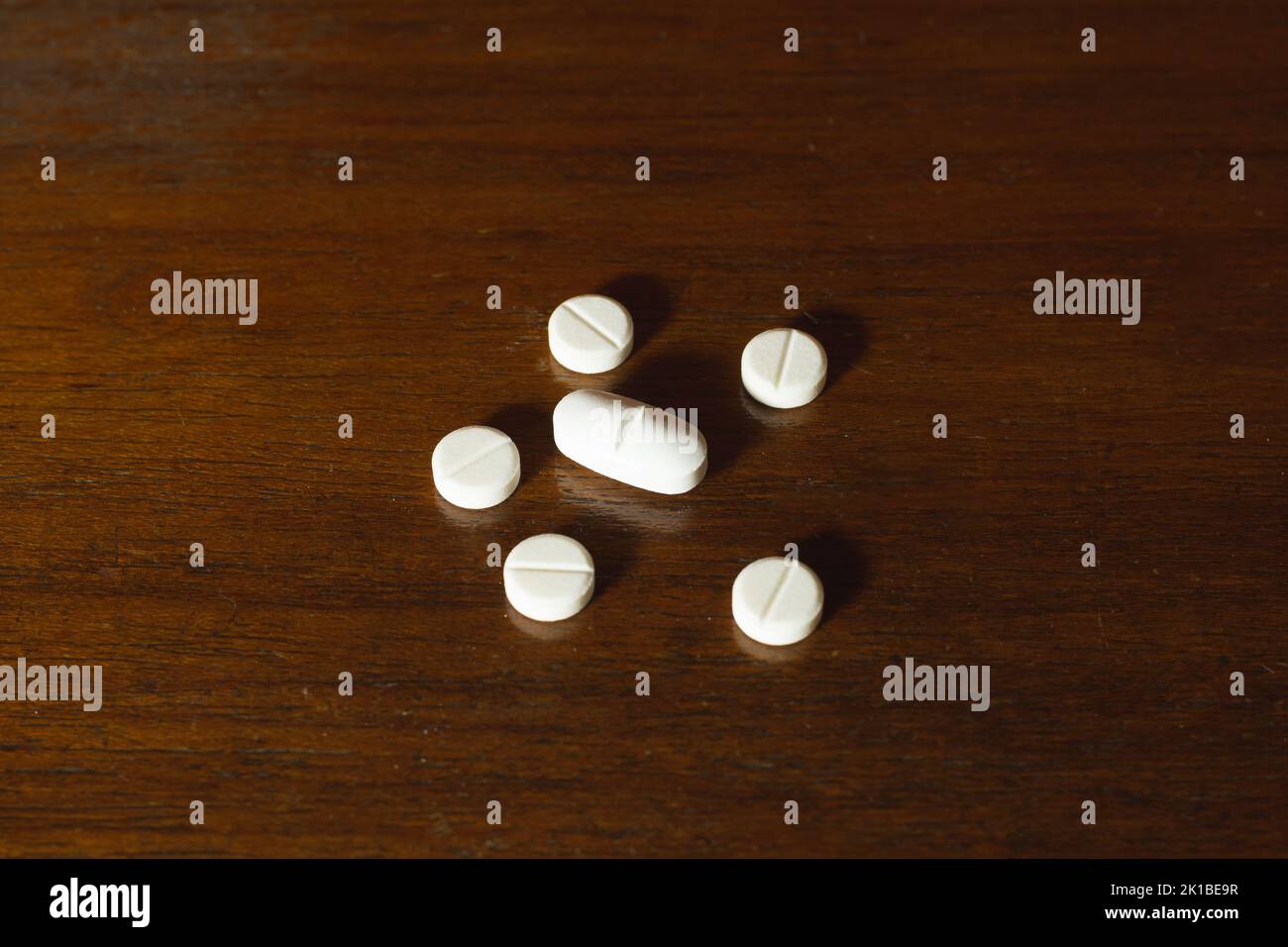Semplice pila di pillole bianche, medicine, pillole impilate su sfondo marrone. Forniture mediche. Foto Stock