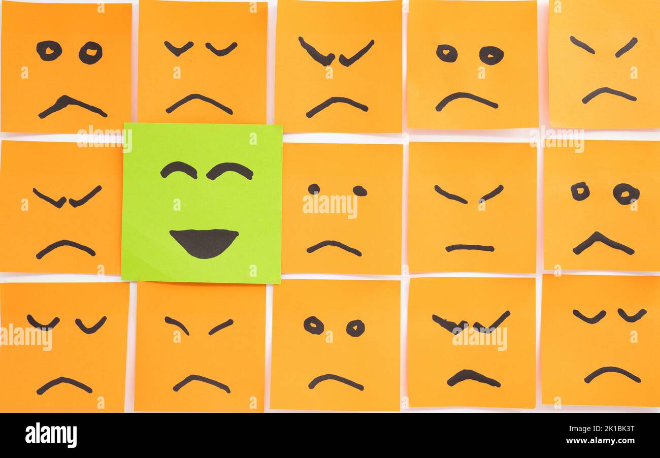 Concetto per un atteggiamento positivo fatto con le carte che assomiglia ai volti tristi con uno che ha sorriso e si distingue Foto Stock