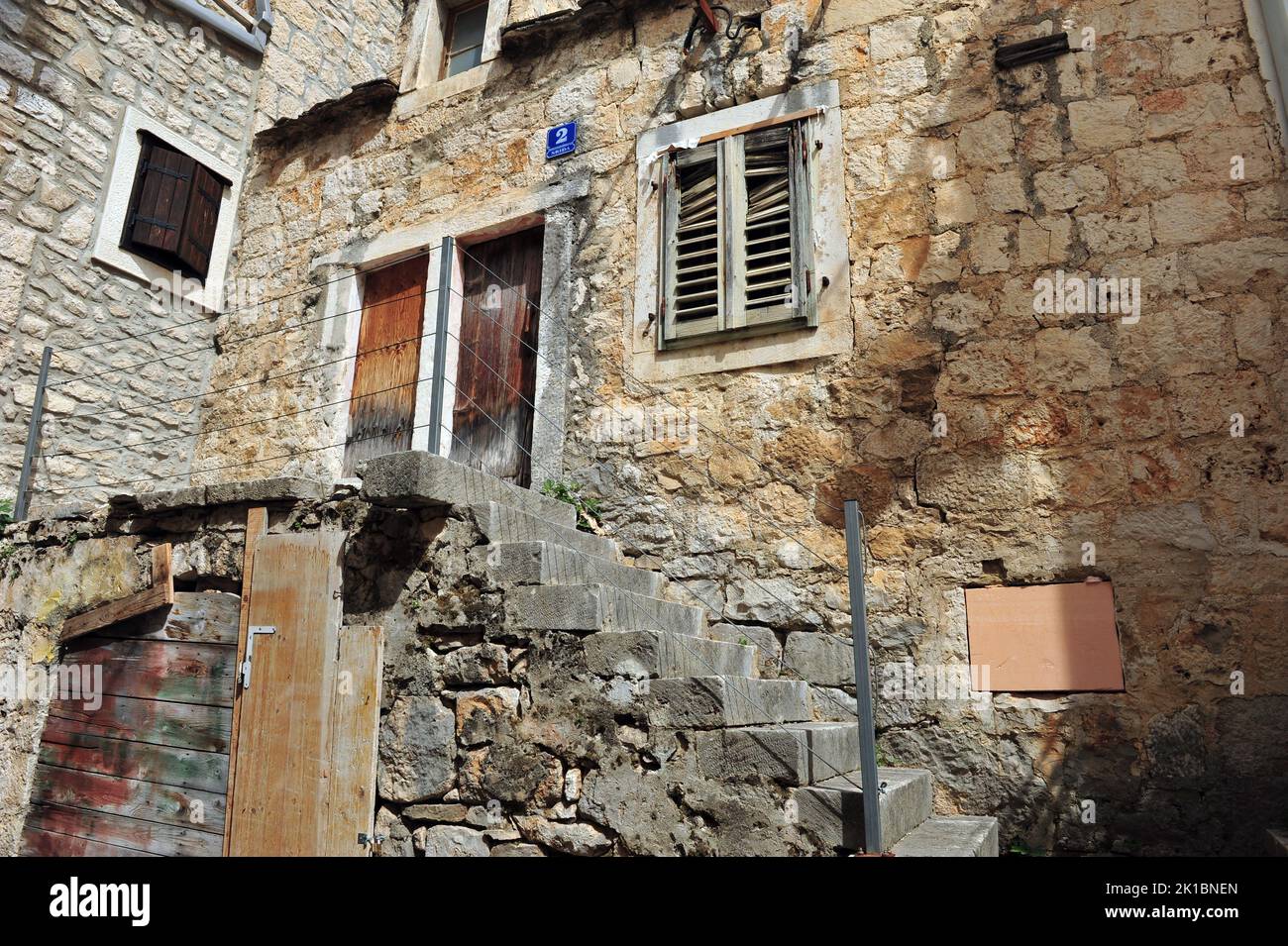 Edificio medievale con scalinata di fronte. Persiane della finestra rotte e pareti in decadimento. Foto Stock