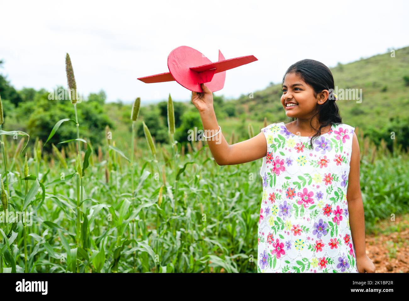 Tracking shot di felice ragazza sorridente bambino giocare con l'aereo durante le vacanze - concetto di libertà, sogno d'infanzia e obiettivo futuro. Foto Stock
