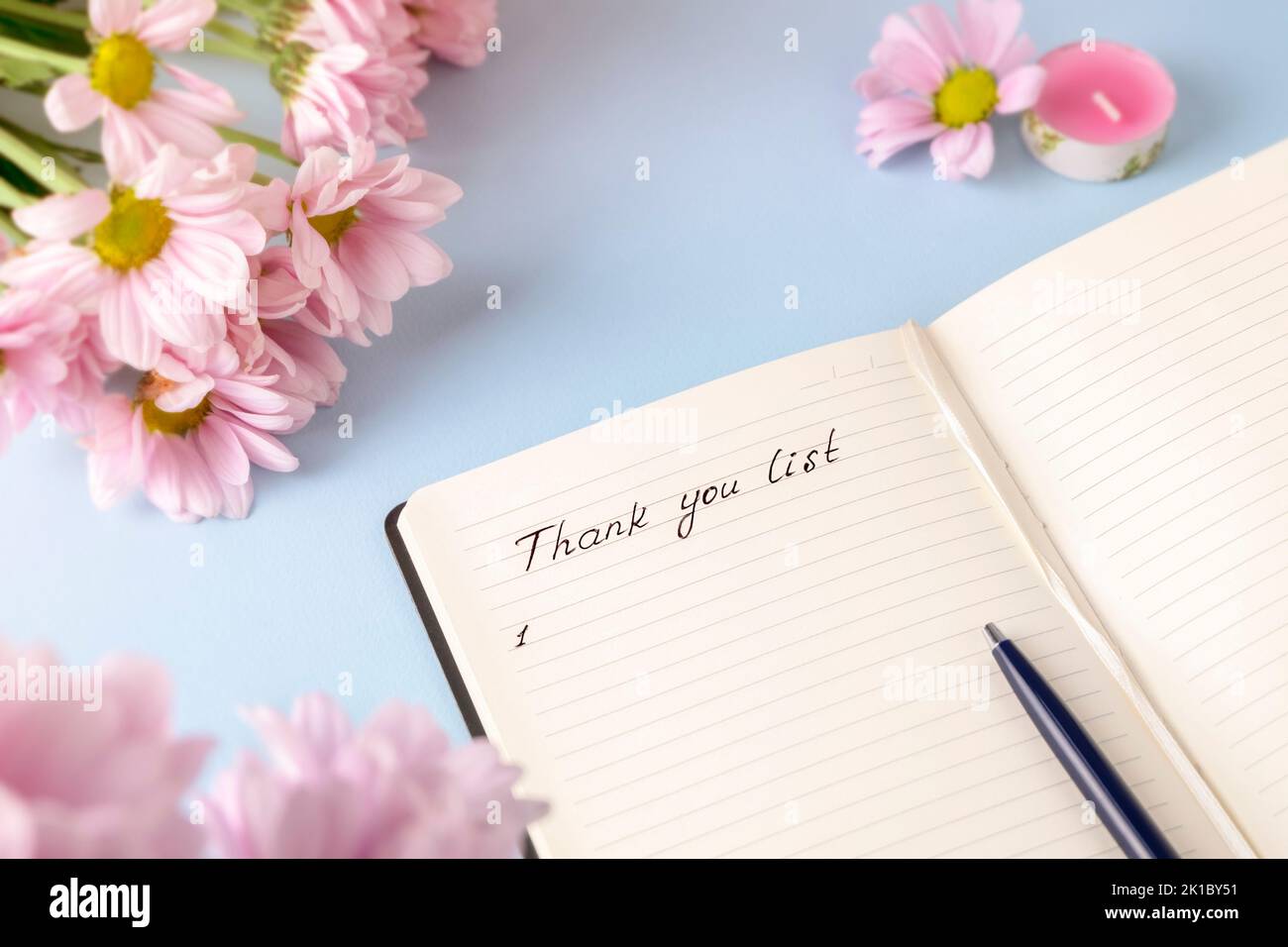 Parole manoscritte grazie elenco in un diario personale su uno sfondo azzurro con fiori rosa. Concetto di rivista di gratitudine Foto Stock