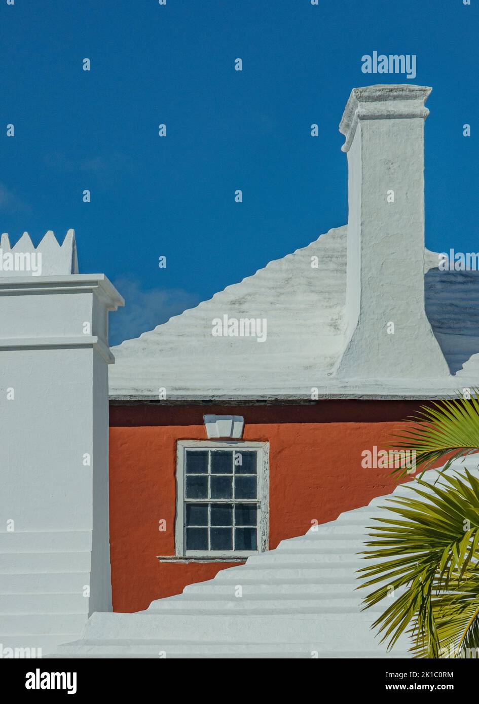 Architettura Bermuda Deep Orange-Red Casa incorniciata all'interno Di Un bianco Chimney & Roof & Bright Blue Sky Close Up Foto Stock