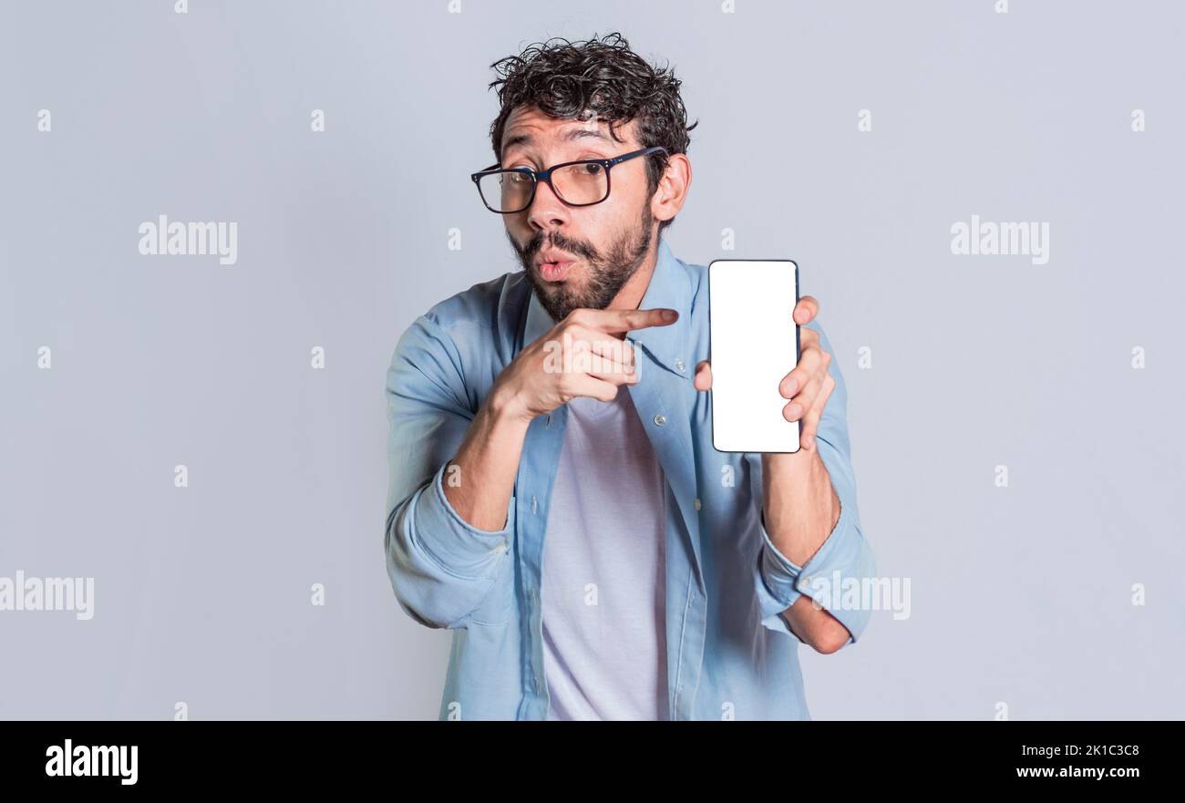 Uomo stupito che mostra lo schermo del cellulare, persona scioccata che mostra e indica lo schermo del suo smartphone, persone stupite che mostra e indica la cella vuota Foto Stock