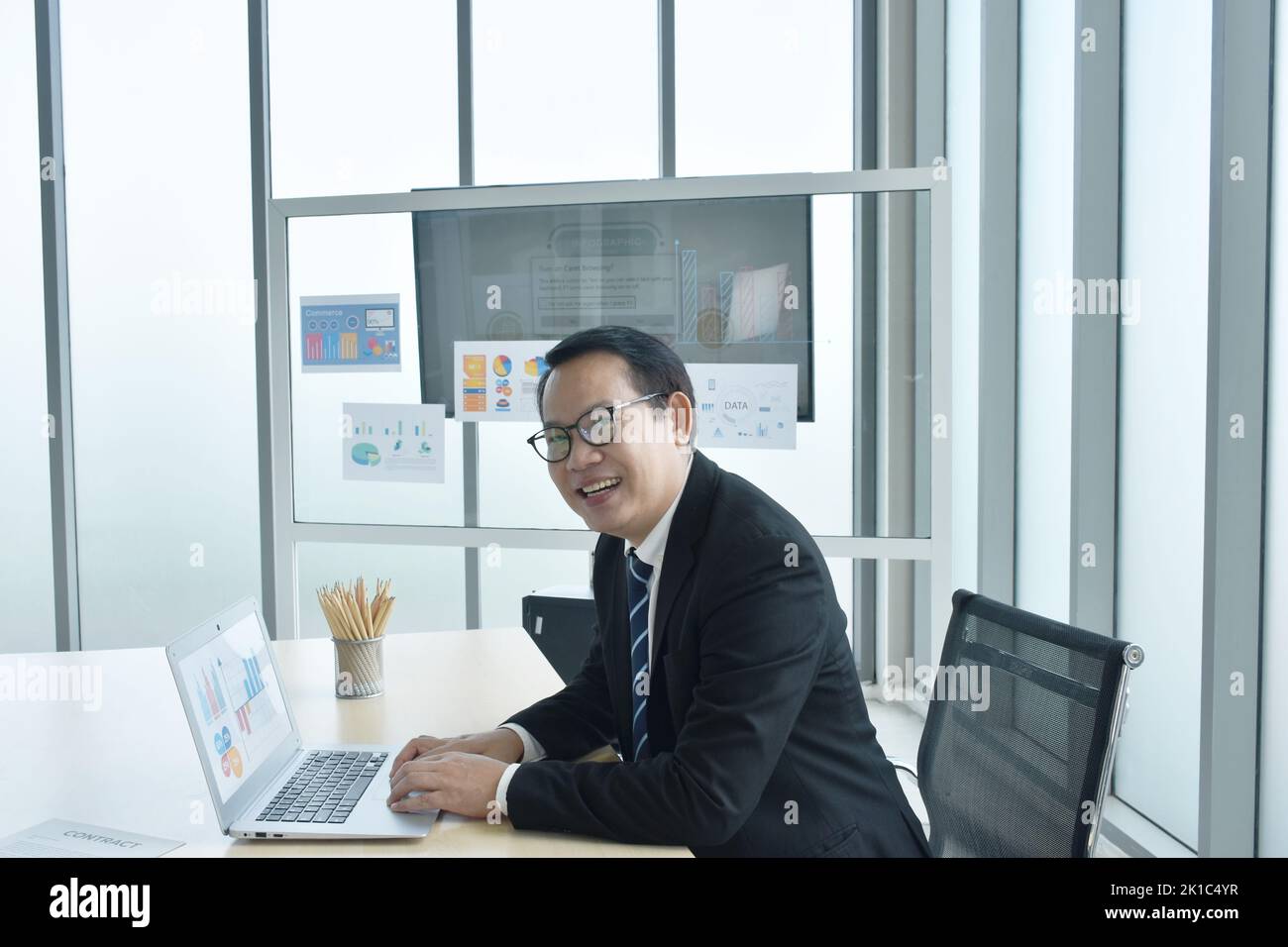 Buon uomo d'affari asiatico che usa un computer portatile in ufficio Foto Stock