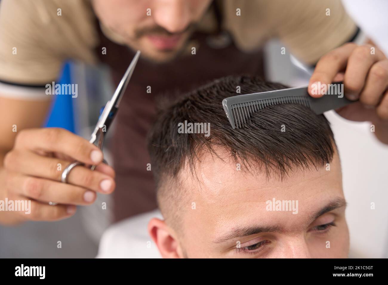 Lavoratore impegnato barbershop che è occupato pettinare e tagliare i capelli Foto Stock