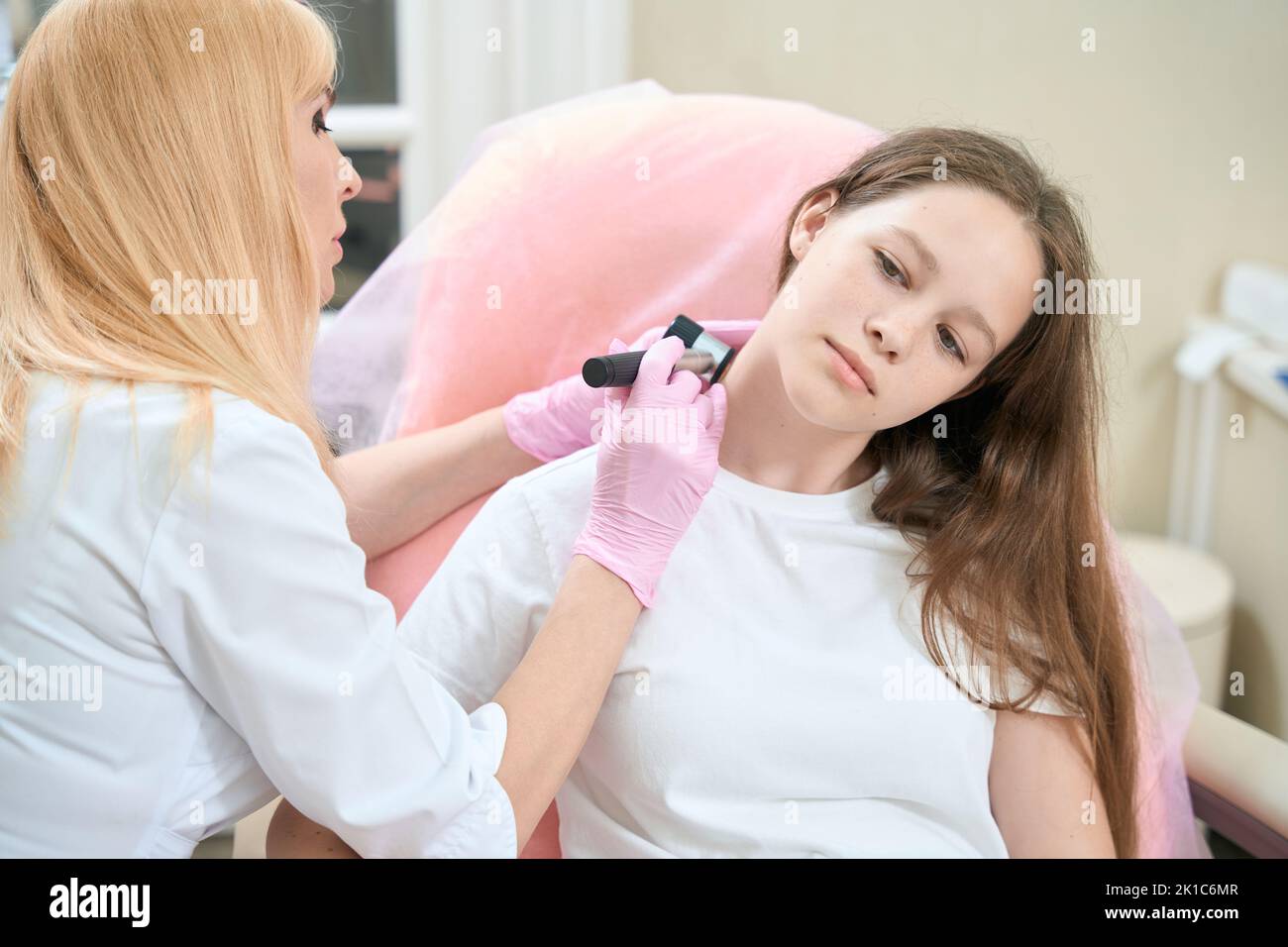 Oncologo medico esamina il collo della ragazza adolescente con dermatoscopio Foto Stock