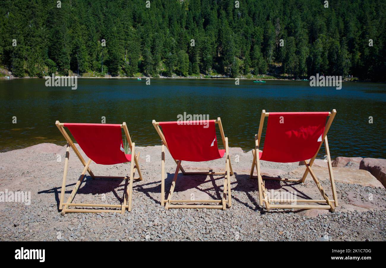 Tre sedie a sdraio rosse, vuote, Mummelsee, Seebach, Parco Nazionale della Foresta Nera, Baden-Wuerttemberg, Germania Foto Stock