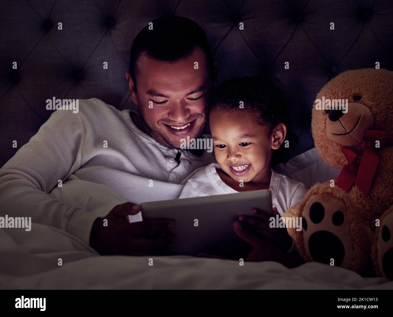 Notte, tablet e uomo e ragazza a letto guardando un film, serie o spettacolo per l'intrattenimento. Amore, sorriso e felice padre e figlia rilassarsi a casa Foto Stock