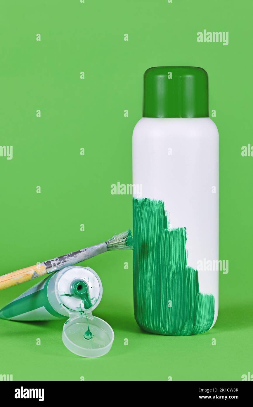 Concetto di lavaggio del verde con bottiglia di plastica bianca verniciata di verde Foto Stock