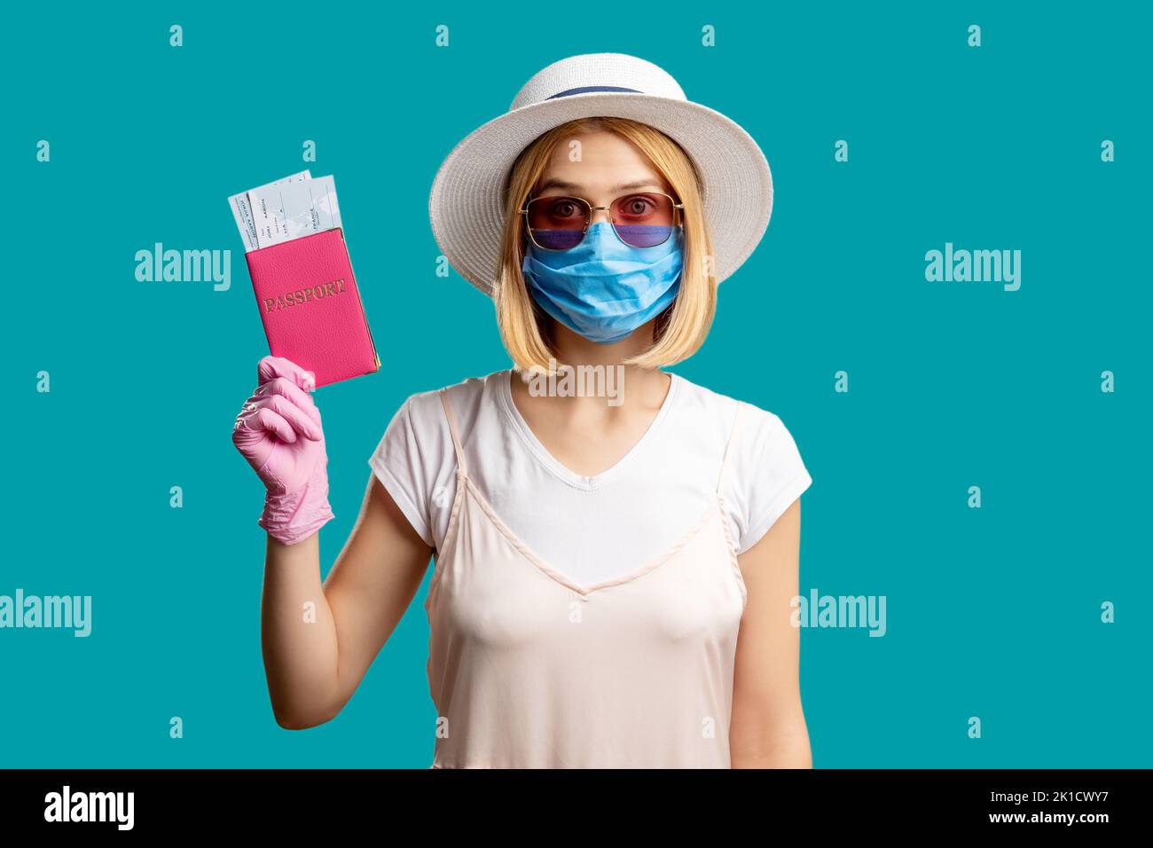 Prevenzione delle pandemie. Limitazione della corsa. Donna in estate vestito maschera protettiva guanti rosa in possesso di un documento d'identità straniero con biglietti. Guardando l'isolamento della videocamera Foto Stock